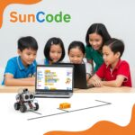 Một nhóm trẻ em ngồi quanh bàn, hào hứng lập trình trên laptop với giao diện Scratch đầy màu sắc. Bên cạnh là robot mBot đang di chuyển trên đường kẻ sẵn. Logo SunCode được đặt ở góc trên, với tông màu xanh dương và cam thân thiện.